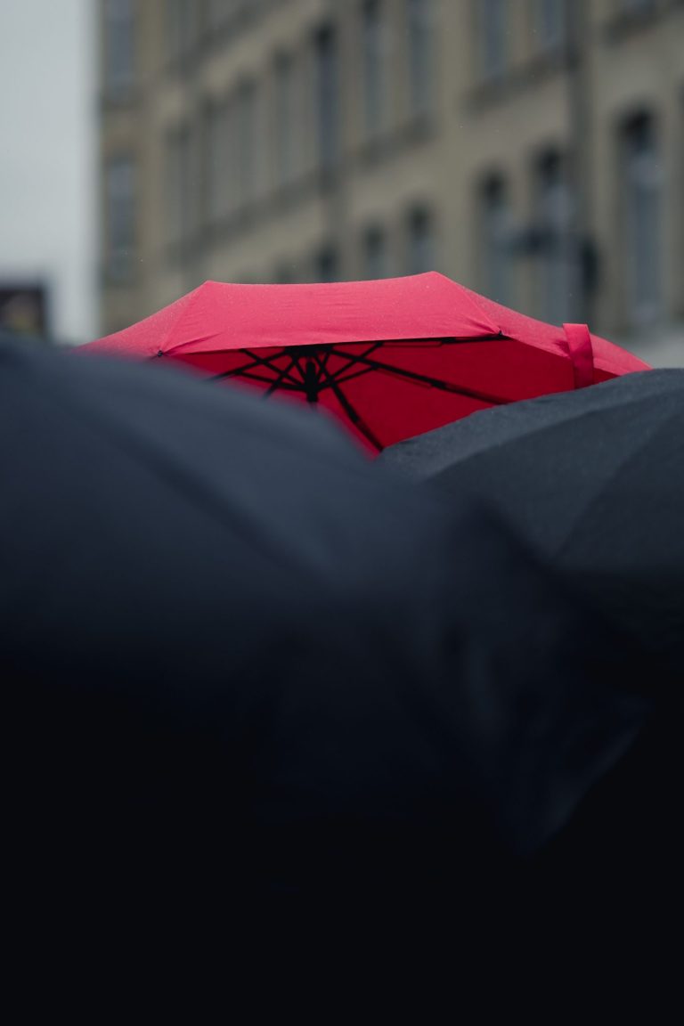 Red umbrella protecting a business professional